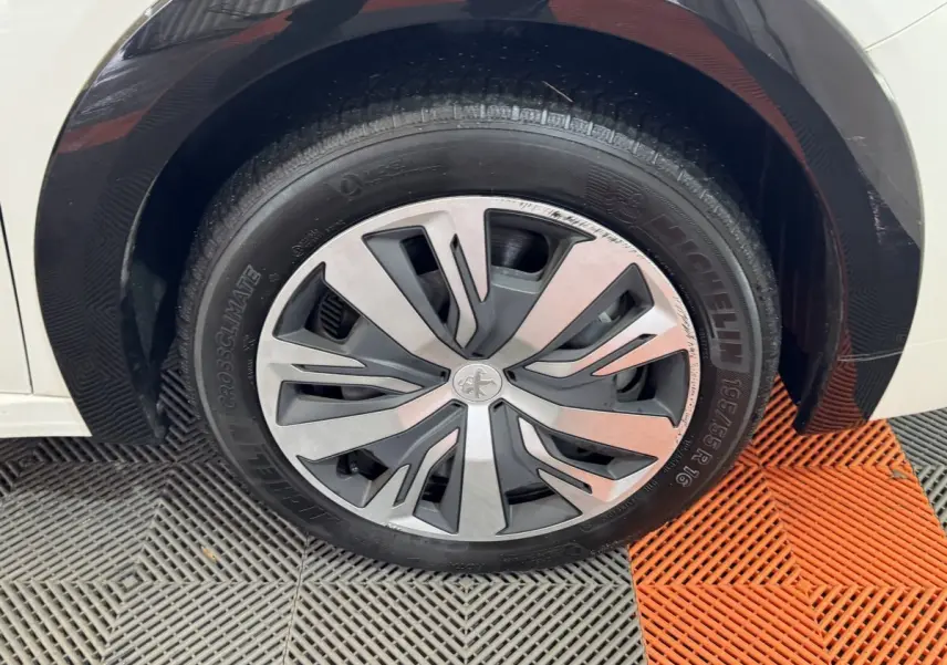 Gros plan sur la roue avant droite d’une Peugeot 208 électrique blanche avec jante spécifique et pneu Michelin.