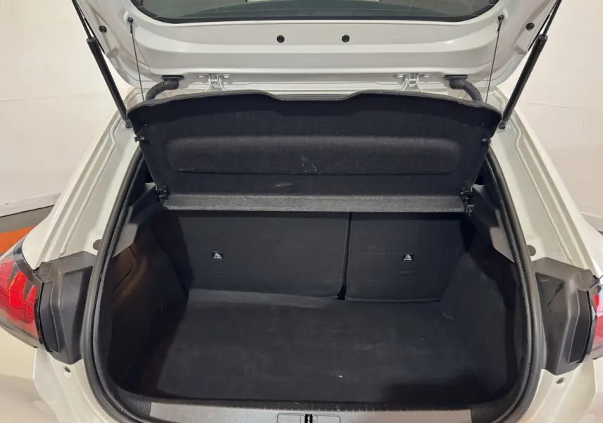Coffre ouvert vu de l'arrière d'une Peugeot 208 Electrique Active Business blanche, intérieur noir et banquette rabattable.