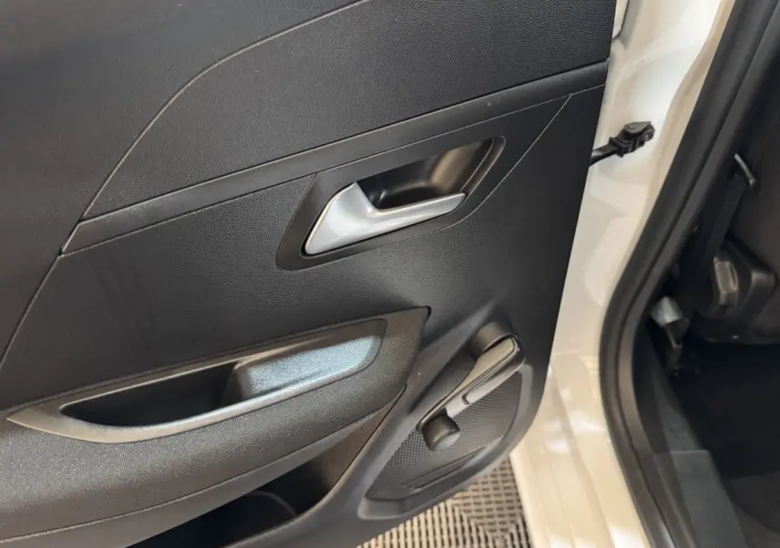 Vue rapprochée de la porte arrière droite noire avec poignée argentée et manivelle de vitre d'une Peugeot 208 électrique blanche.
