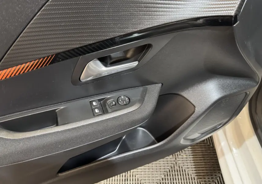 Gros plan sur la porte avant gauche noire avec poignée argentée et commandes des vitres de la Peugeot 208 Electrique Active Business.