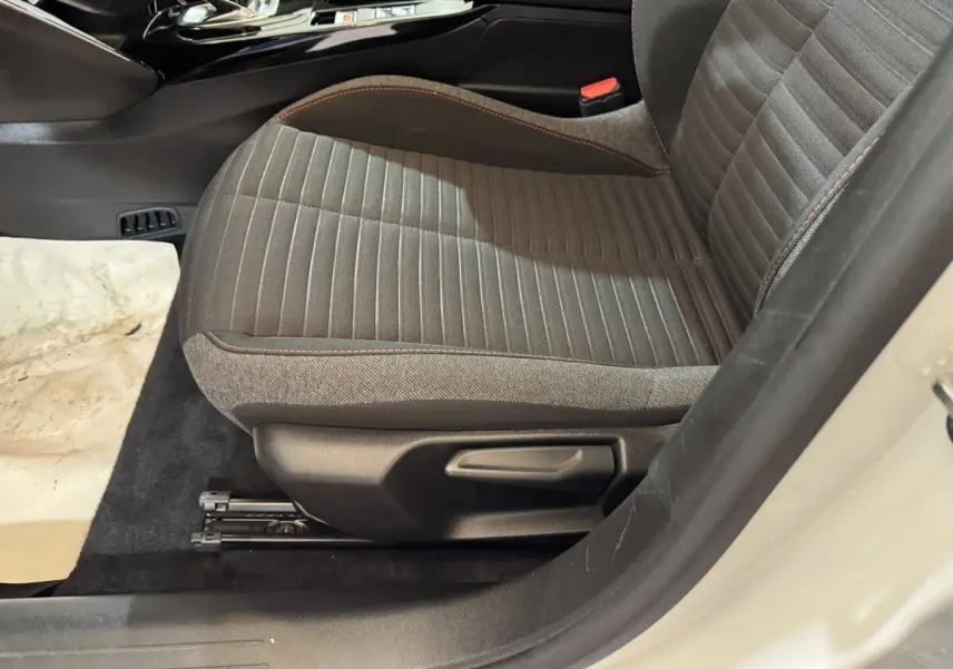 Vue latérale du siège avant droit gris foncé avec surpiqûres rouges dans l'habitacle d'une Peugeot 208 électrique 2020.
