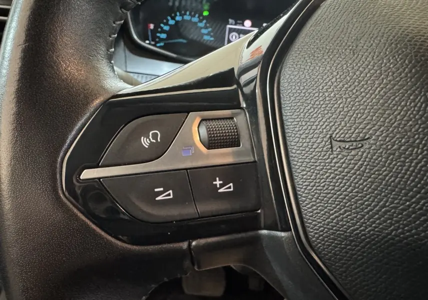 Gros plan sur les commandes vocales et volume du volant cuir noir de la Peugeot 208 Electrique Active Business 2020.