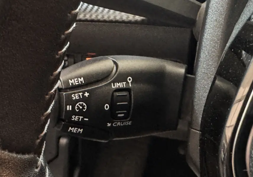 Gros plan sur la commande de régulateur de vitesse au volant cuir de la Peugeot 208 électrique Active Business.