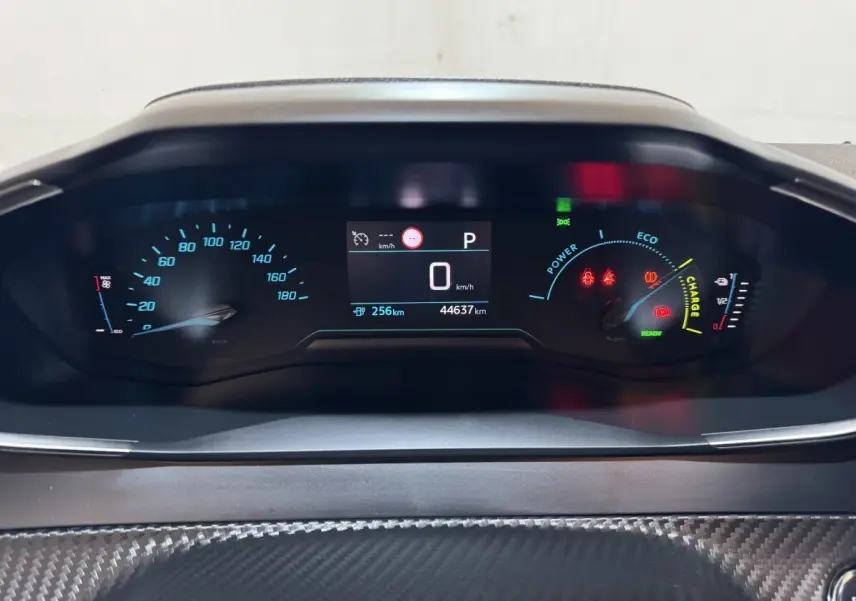 Tableau de bord numérique de Peugeot 208 électrique, affichage central avec vitesse à 0 km/h et jauges colorées.
