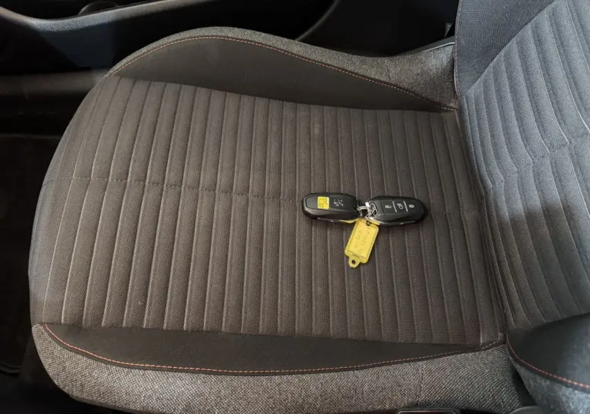 Gros plan sur la banquette arrière grise de la Peugeot 208 électrique avec les clés posées dessus.