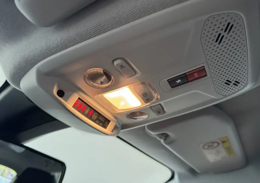 Plafonnier intérieur allumé avec commandes d’éclairage et bouton SOS dans une Peugeot 208 électrique, vue de dessous.