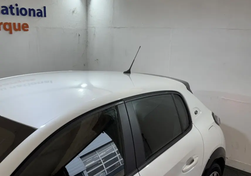 Vue partielle côté droit arrière d'une Peugeot 208 Electrique Active Business blanche, avec antenne de toit et vitres teintées.