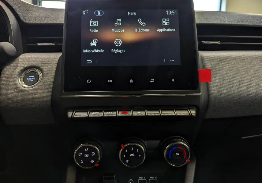 Vue rapprochée de la console centrale de la Renault Clio V 2025, écran tactile et commandes de climatisation visibles.