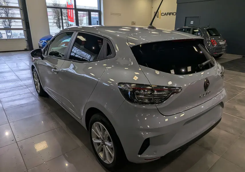 Renault Clio V gris Rafale vue 3/4 arrière droit en intérieur, avec feux arrière LED et vitres teintées.