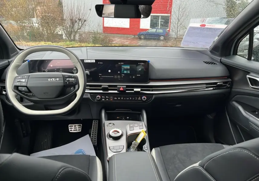 Vue intérieure avant du Kia Sportage 2026, tableau de bord moderne avec écran tactile et volant cuir bicolore.