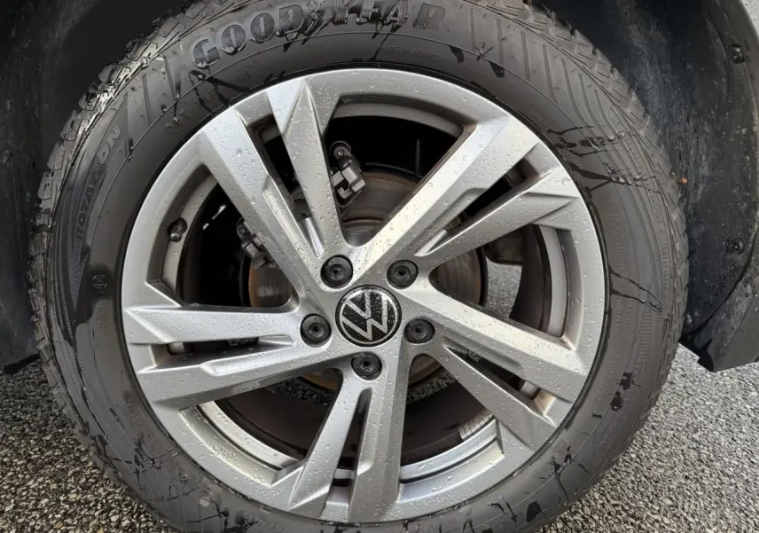 Gros plan sur la jante alliage léger Valencia grise avec logo Volkswagen au centre, pneu Goodyear mouillé.