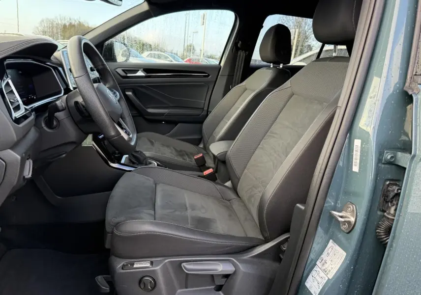 Vue intérieure côté conducteur du Volkswagen T-Roc 2025 bleu, sièges avant Ergoactive en tissu et alcantara gris.