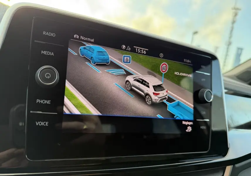 Écran tactile intérieur montrant l'assistance IQ.DRIVE avec vue 3D de deux véhicules sur route et panneau 60 km/h.