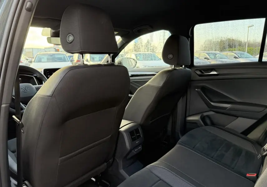 Vue intérieure arrière du Volkswagen T-Roc 2025, sièges noirs avec surpiqûres et détails tissu Alcantara.