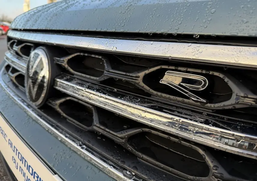 Gros plan sur la calandre avant bleue du Volkswagen T-Roc 2025 avec logo R et gouttes d'eau visibles.