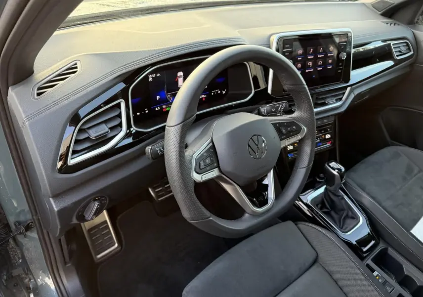 Vue intérieure côté conducteur du Volkswagen T-Roc 2025, volant cuir multifonction et tableau de bord digital.