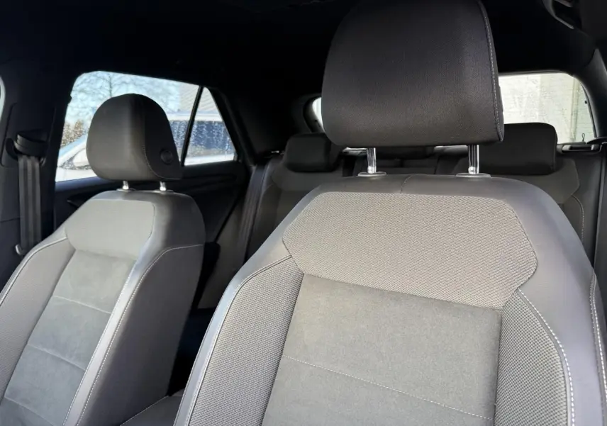 Gros plan sur les sièges avant gris du Volkswagen T-Roc 2025 avec appuis-tête et intérieur sombre.