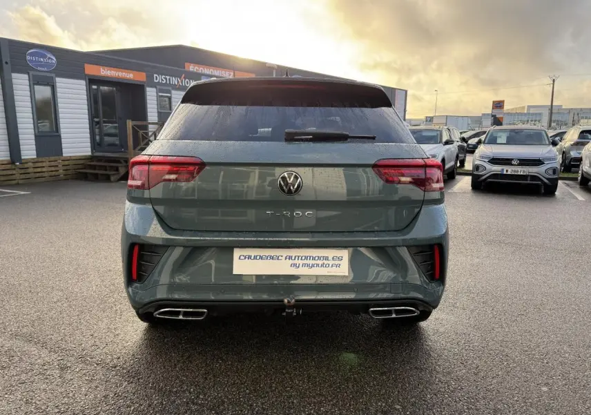 Vue arrière du Volkswagen T-Roc bleu avec double sortie d’échappement et attelage amovible visible.