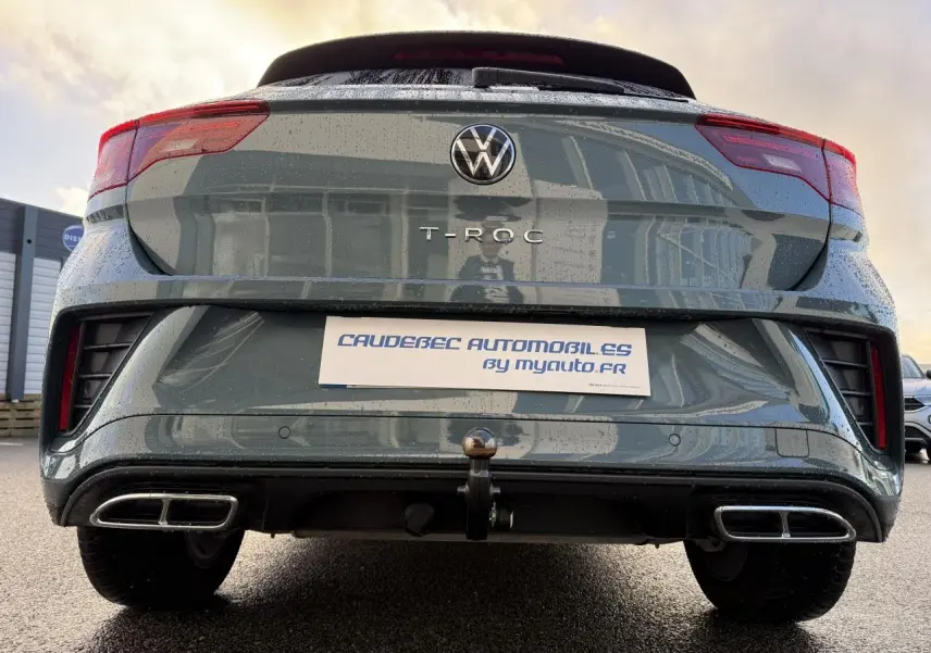 Vue arrière basse d'un Volkswagen T-Roc bleu avec attelage amovible et double sortie d'échappement chromée.