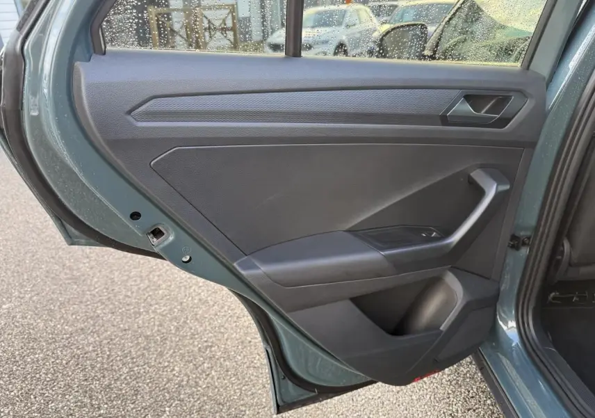 Vue rapprochée de la porte arrière gauche bleu du Volkswagen T-Roc 2025, montrant la garniture intérieure noire.