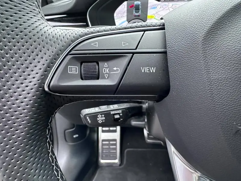 Gros plan sur les commandes au volant côté gauche d'un Audi A5 Cabriolet noir avec affichage GPS en arrière-plan.