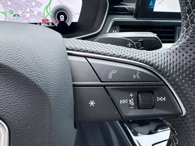 Gros plan sur les commandes vocales et audio au volant côté gauche de l'Audi A5 Cabriolet noir 2023.