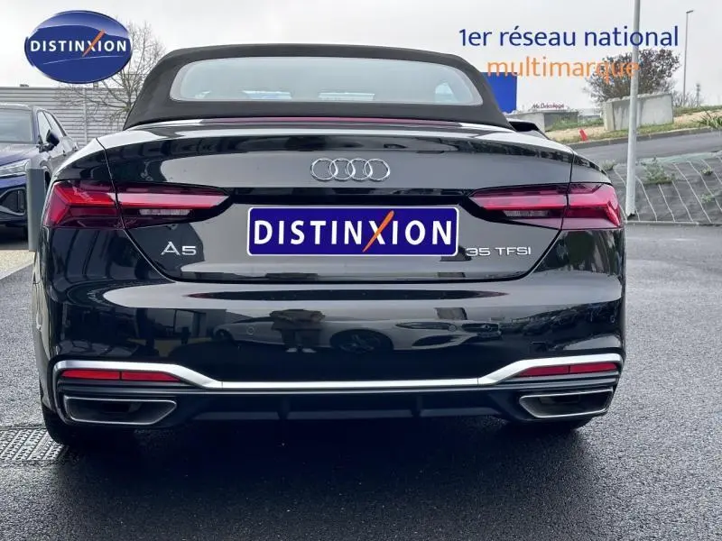 Vue arrière d'une Audi A5 Cabriolet 35 TFSI noire avec capote noire et double sortie d'échappement chromée.