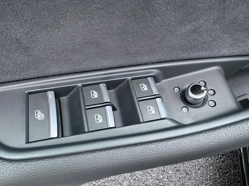 Gros plan sur les commandes de lève-vitres et réglage des rétroviseurs côté conducteur de l'Audi A5 Cabriolet noir.