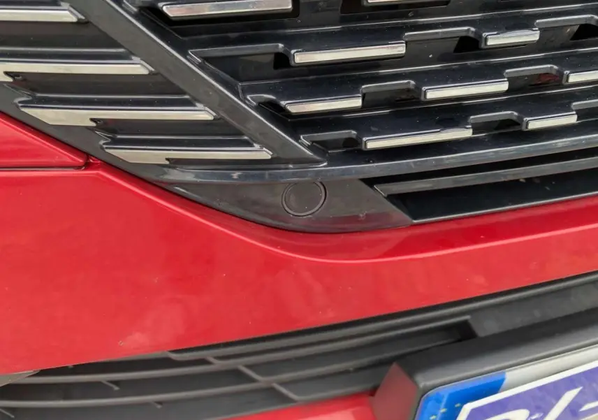 Gros plan sur la calandre avant rouge Elixir de la Peugeot 308 GT 2022 avec capteur de caméra 360° intégré.