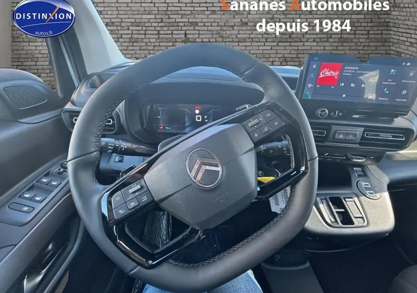 Vue intérieure centrée sur le volant cuir noir et le tableau de bord numérique du Citroën Berlingo blanc 2025.