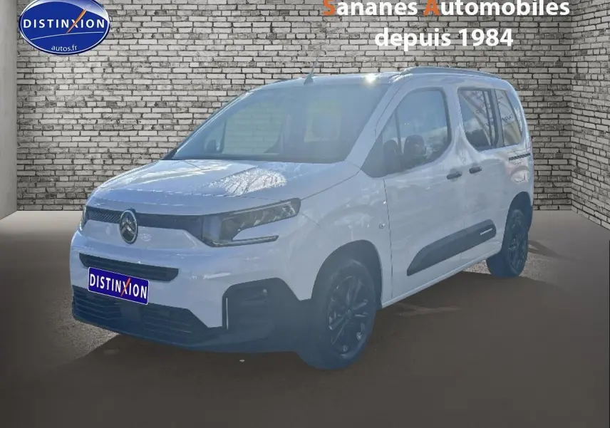 Vue 3/4 avant droit d'un Citroën Berlingo blanc avec barres de toit noires et jantes alliage sombres.