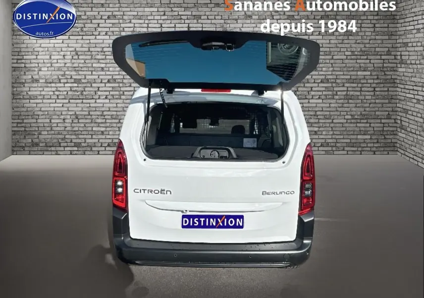 Vue arrière d'un Citroën Berlingo blanc avec hayon ouvert, feux rouges verticaux et pare-chocs noir.