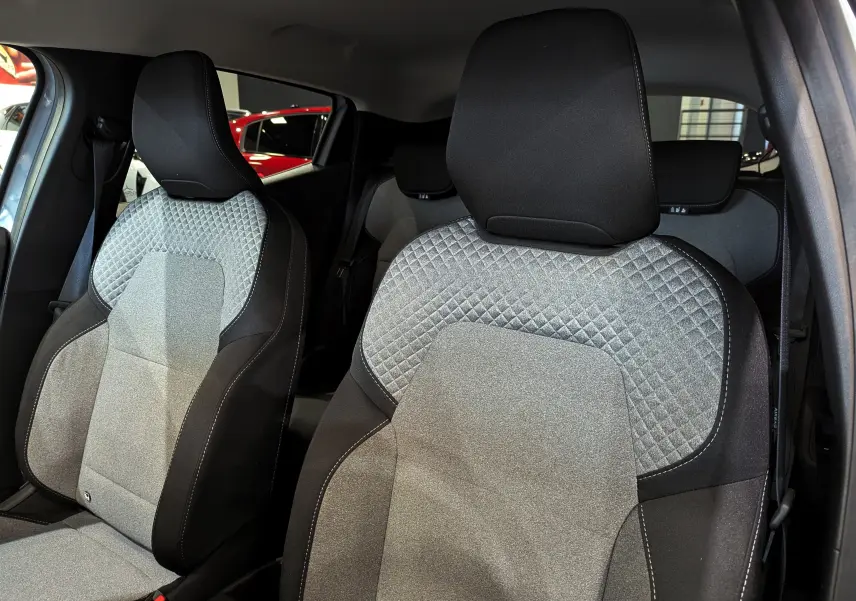 Gros plan sur les sièges avant en tissu gris et noir de la Renault Clio V 2025, intérieur moderne et confortable.