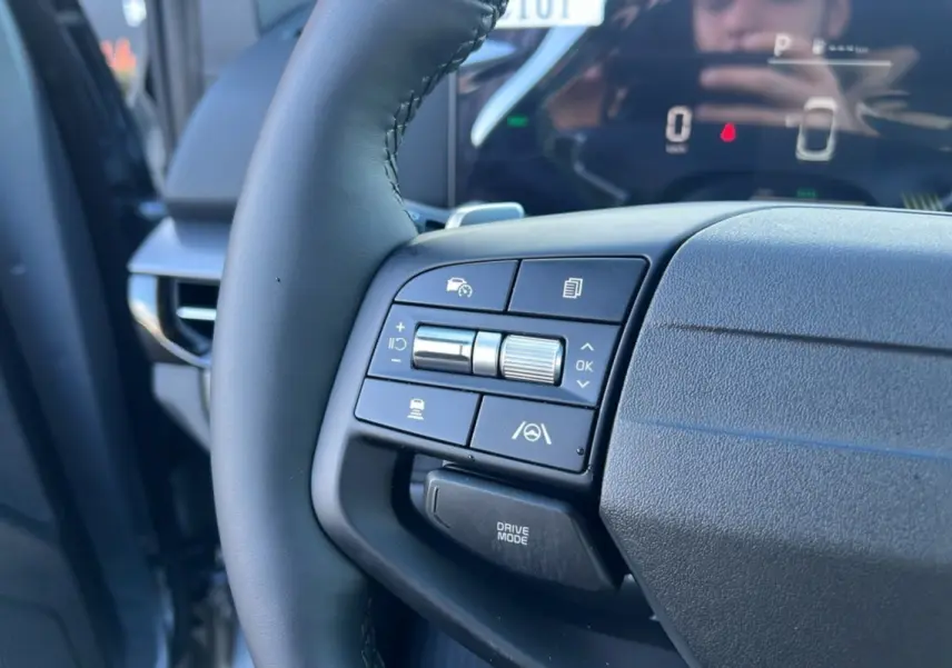 Gros plan sur le volant cuir multifonctions du Kia Sportage 2026 gris perle, avec commandes d’aide à la conduite visibles.