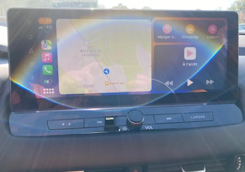 Écran tactile central du Nissan Qashqai 2023 noir, affichant navigation et commandes multimédia avec boutons physiques en dessous.