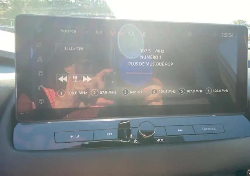 Écran tactile multimédia du Nissan Qashqai 2023 affichant la liste FM avec commandes volume et caméra.