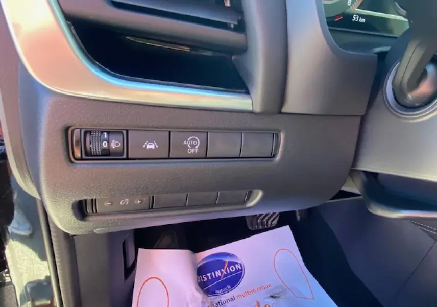 Détail des commandes d'aide à la conduite sous le tableau de bord côté gauche du Nissan Qashqai noir 2023.