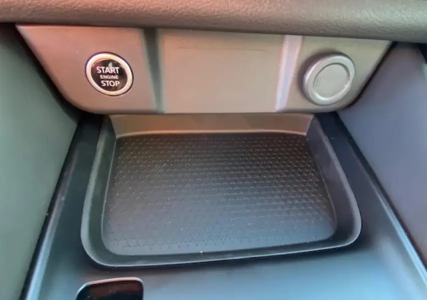 Détail de la console centrale du Nissan Qashqai 2023 noir avec bouton start/stop et espace de rangement texturé.
