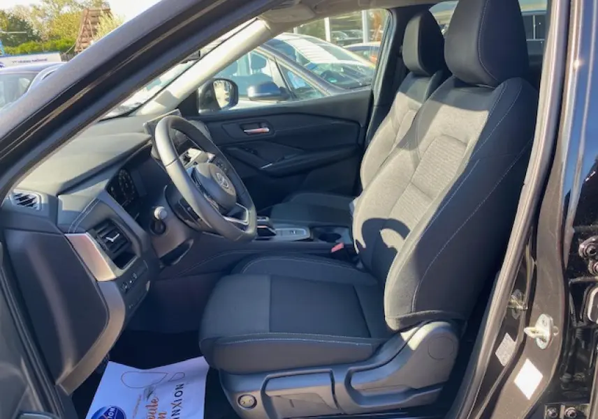 Intérieur côté conducteur du Nissan Qashqai noir 2023, montrant sièges en tissu et tableau de bord moderne.