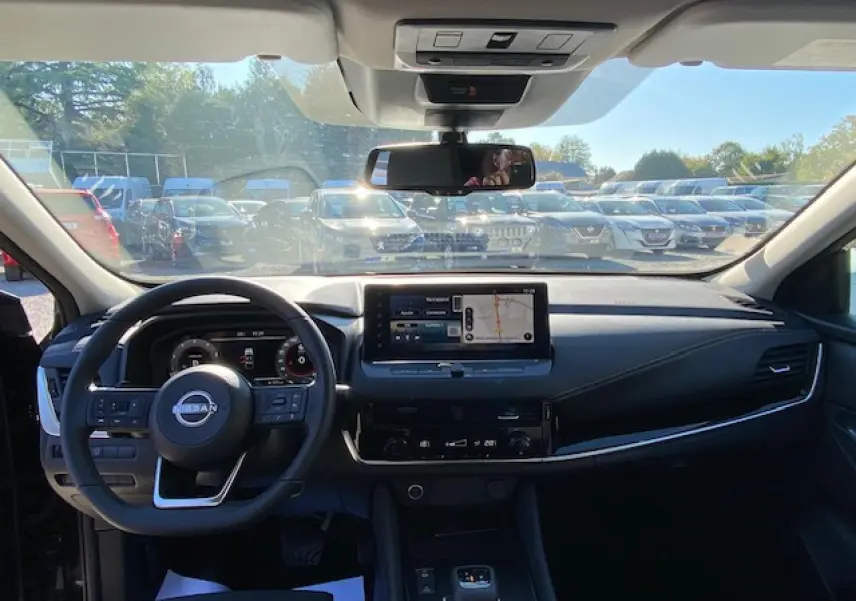 Vue intérieure du tableau de bord noir du Nissan Qashqai 2023, avec écran tactile central et volant multifonction.