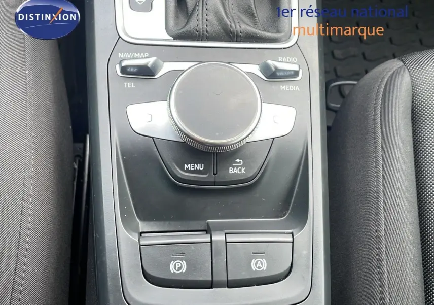 Vue plongeante sur la console centrale noire de l'Audi Q2 35 TFSI S-Line 2023 avec commandes multimédia et frein électronique.