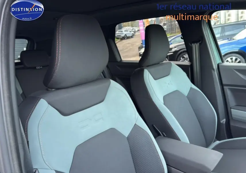 Gros plan sur les sièges avant bicolores gris et vert cèdre du Dacia Bigster 2025, avec accoudoir central visible.