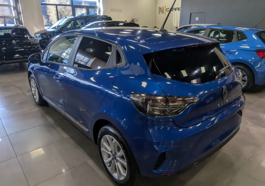 Renault Clio V Bleu Iron vue 3/4 arrière droit en intérieur, avec feux arrière fumés et jantes alliage 16 pouces.