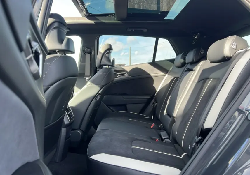 Vue intérieure de la banquette arrière du Kia Sportage gris eclipse avec toit panoramique et sièges en cuir noir et alcantara.