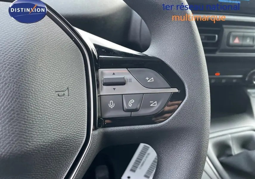 Gros plan sur le volant noir du Peugeot Partner 2025 avec commandes audio et téléphone intégrées.