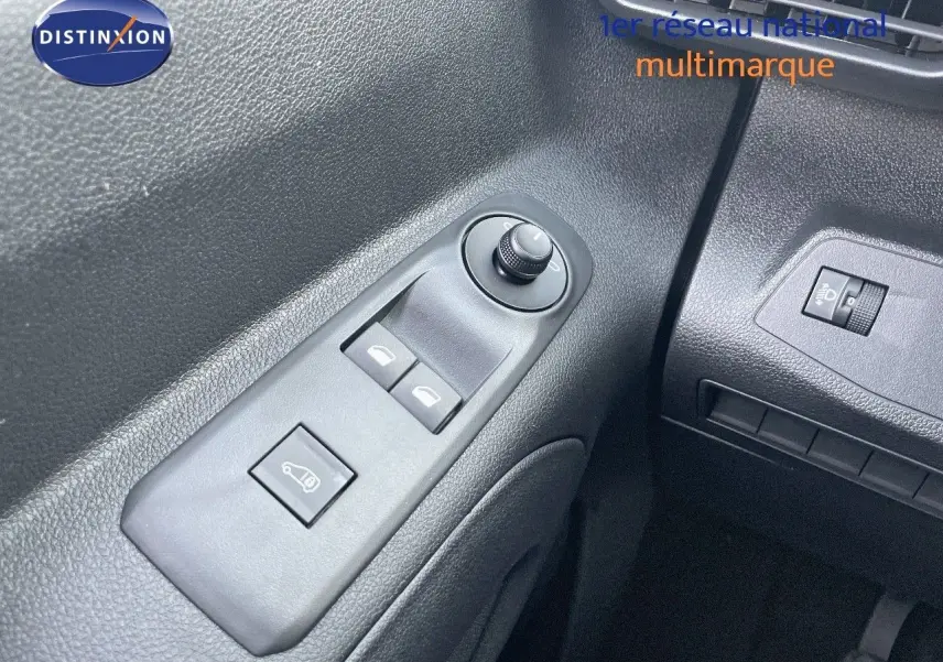 Gros plan sur les commandes de lève-vitres et réglage des rétroviseurs côté gauche du Peugeot Partner 2025, intérieur noir.