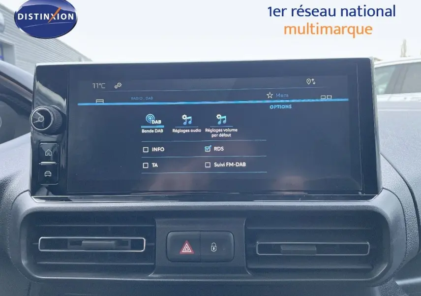 Écran tactile central du tableau de bord du Peugeot Partner 2025, affichant les réglages audio DAB, avec commandes et aérateurs noirs.
