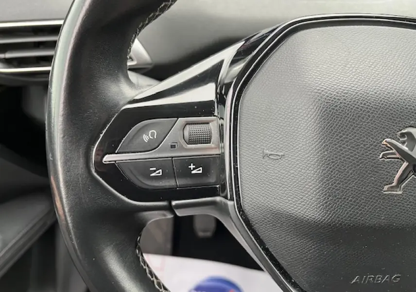 Gros plan sur le volant multifonctions noir du Peugeot 3008 1.5 BlueHDi 130 Allure, avec commandes audio intégrées.
