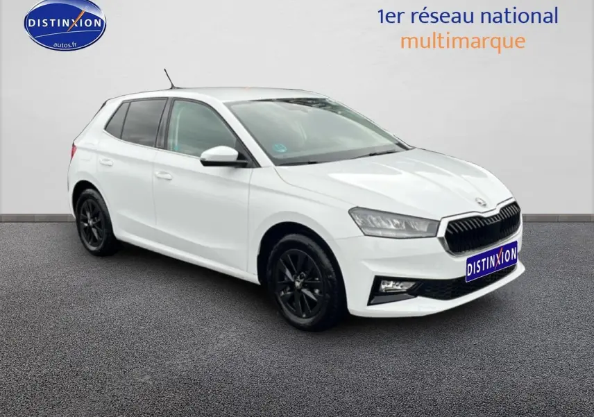 Vue 3/4 avant droite d'une Skoda Fabia blanche avec jantes noires, sur fond neutre intérieur showroom.