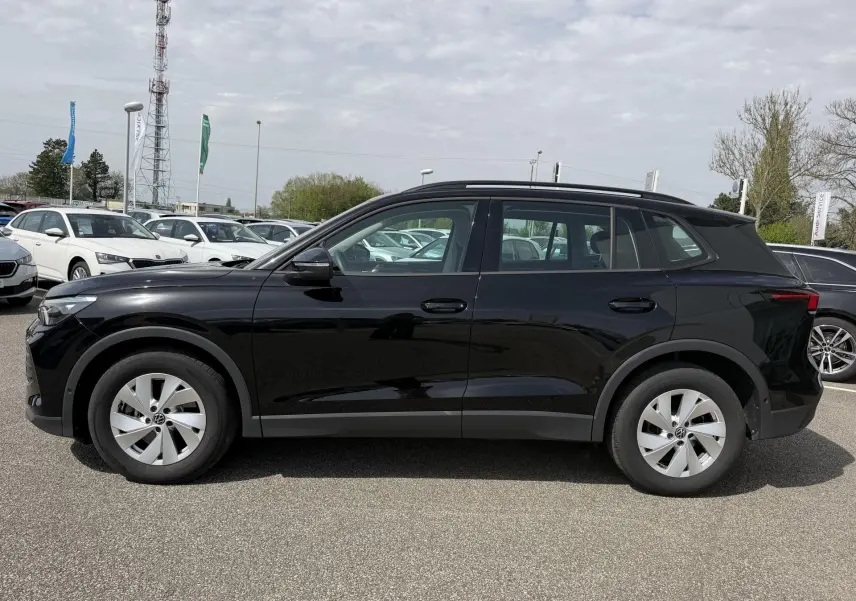 Profil droit d'un Volkswagen Tiguan noir 2025 garé en extérieur, avec jantes alliage légères et lignes épurées.